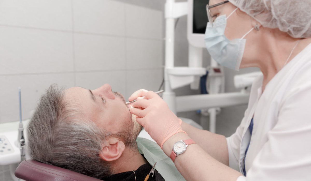 A female dentist treats the teeth of a male patient in a modern office of a dental clinic. Concept of medicine, dentistry and healthcare. Dental equipment