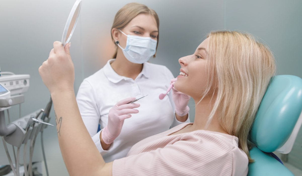 Happy woman smiling looking in the mirror after dental checkup